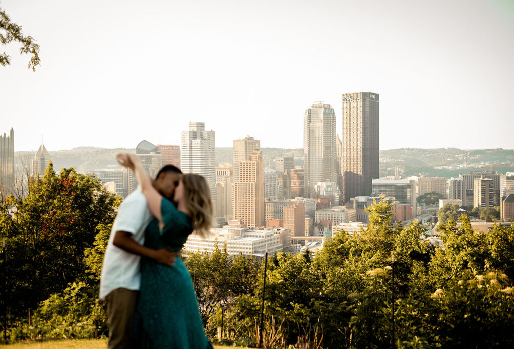 Couple kissing at Emerald Park in the afternoon in front of the city of Pittsburgh