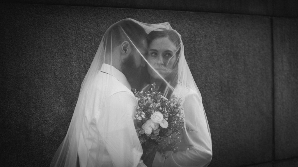 Bride and groom under veil holding bouquet after elopement in downtown Pittsburgh