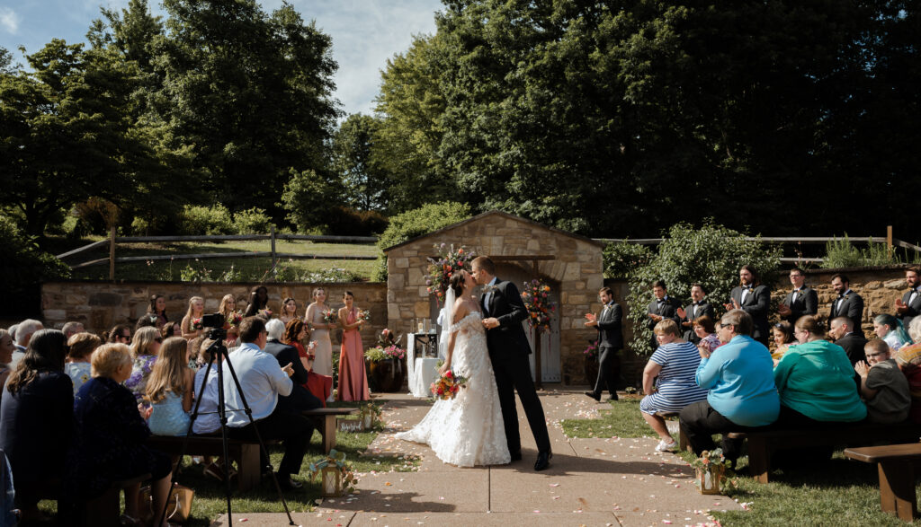 Couple kiss while their guests clap at their ceremony at Phipps Conservatory and Botanical Gardens 