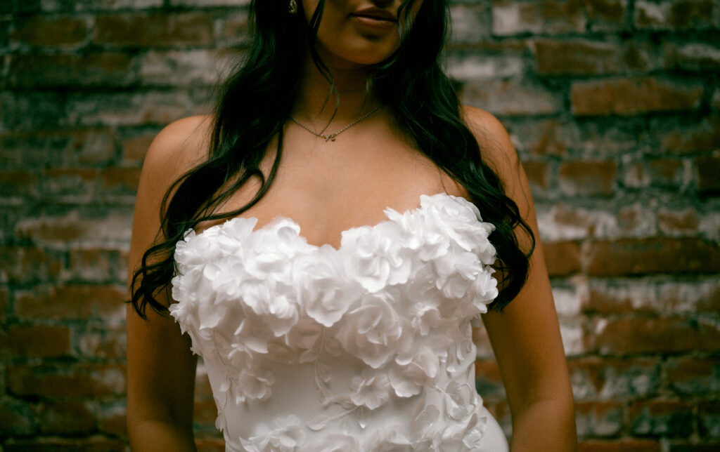 Close up of wedding gown with white pedal flowers. 