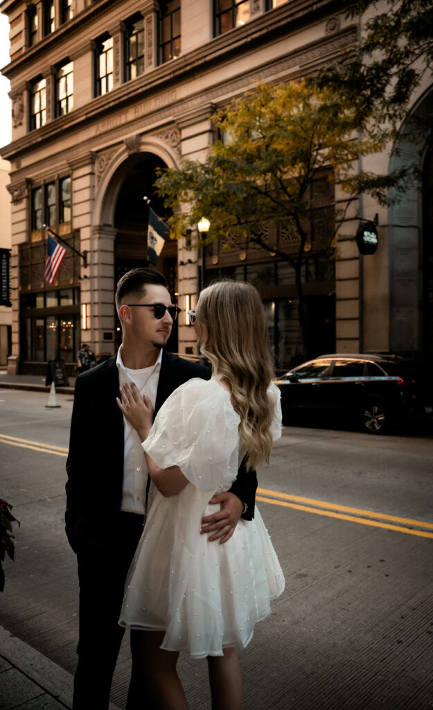 Bride and Groom wearing sunglasses standing in a sidewalk in Downtown Pittsburgh Looking at each other. 