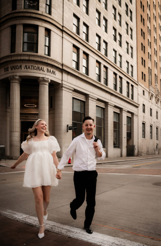 Couple running down Downtown Pittsburgh while holding hands