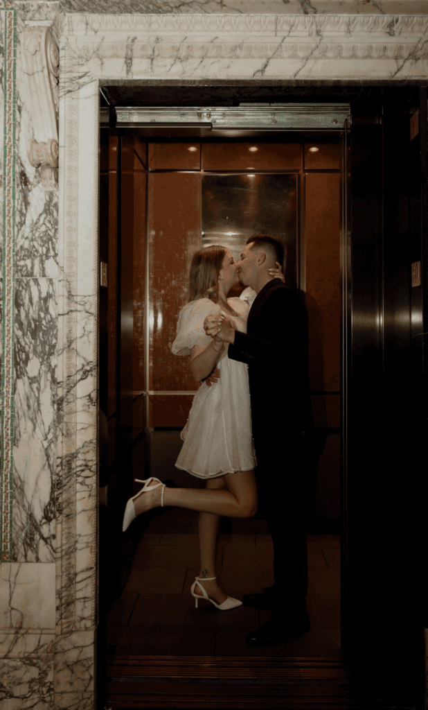 Couple inside an elevator kissing while the elevator doors closes.