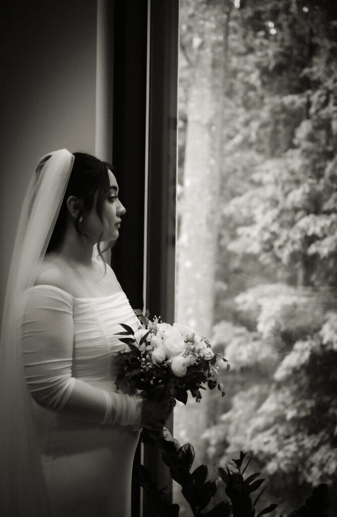 Black and White Bride looking at forest holding a bouquet