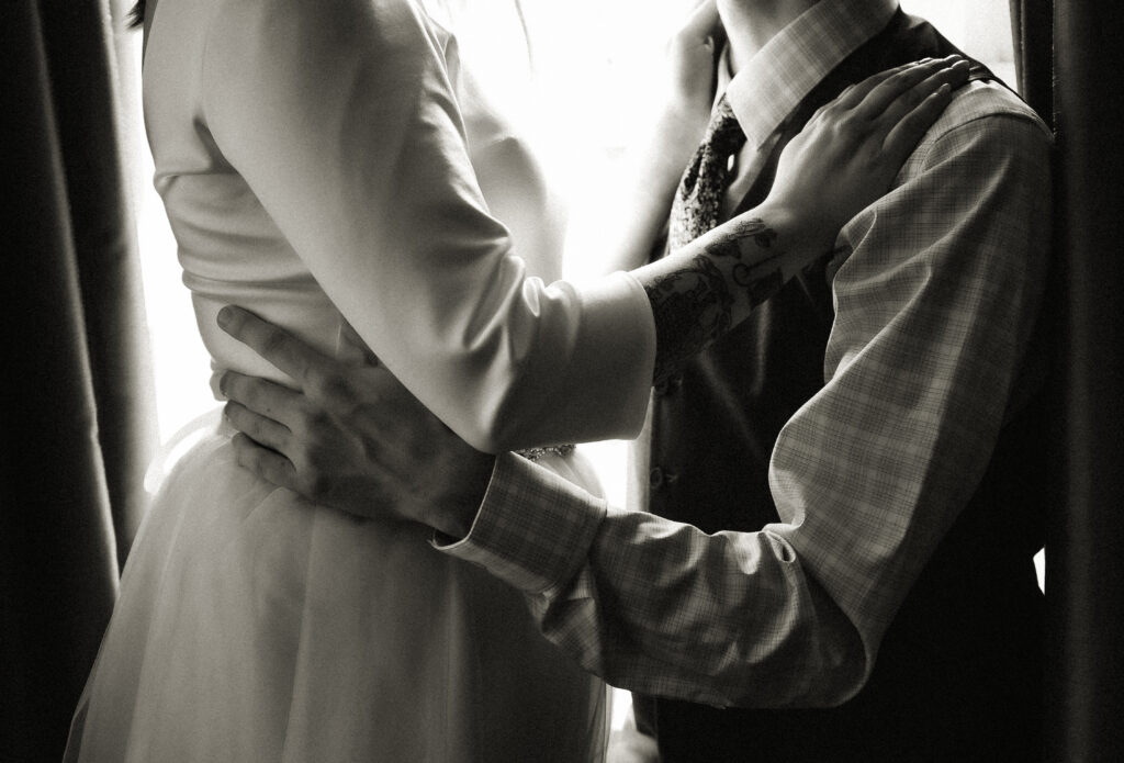 Black and white couple holding each other by a window in black and white