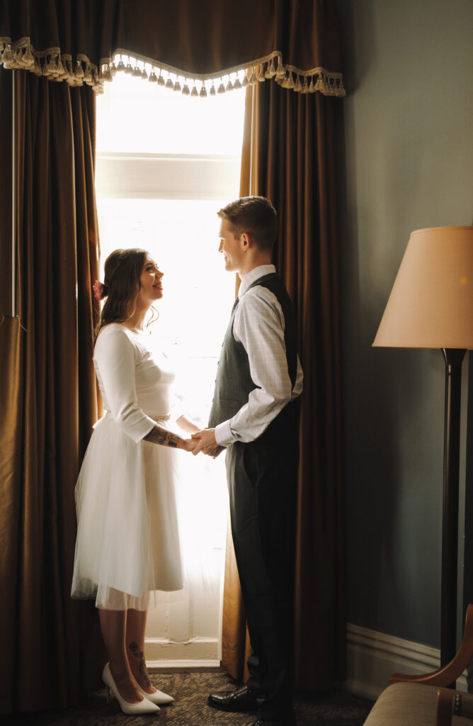 Couple standing in front of a window looking at each other at The Mansion On Fifth Luxury Hotel