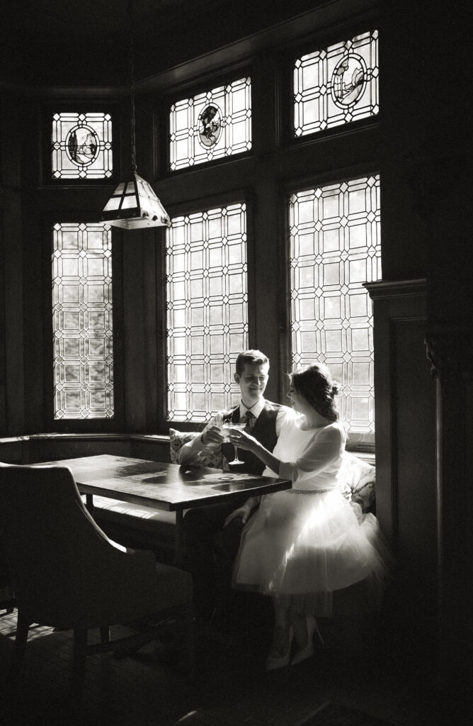 Couple sitting at The Mansion On Fifth Luxury Hotel Restaurant having a drink after wedding ceremony in black and white