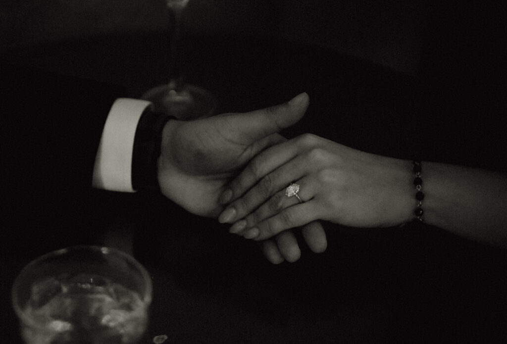 Hands of couple holding each other showing off engagement ring