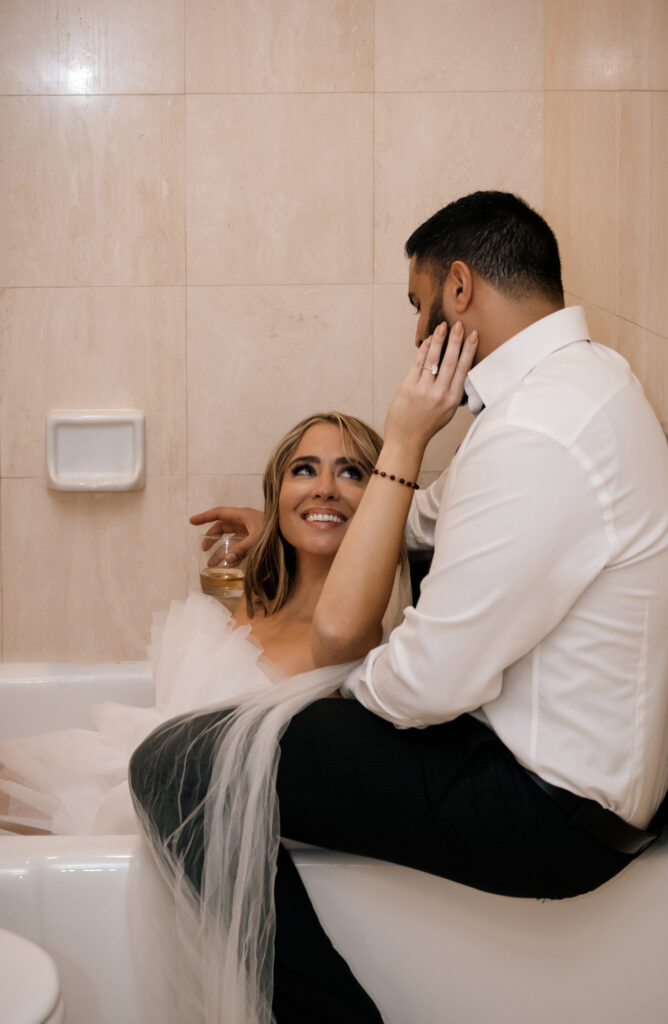 bride and groom at the bathtub on a hotel room looking at each other