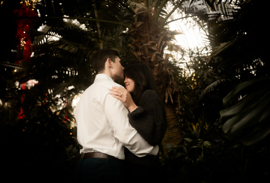 Couple kiss surrounded by plants at the Phipps Botanical Garden