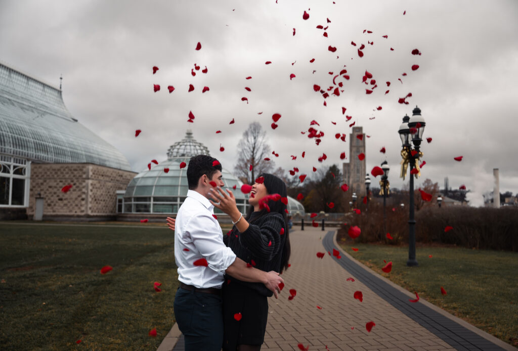 Couple celebrate their Proposal in front of Phipps botanical garden with roses in the air