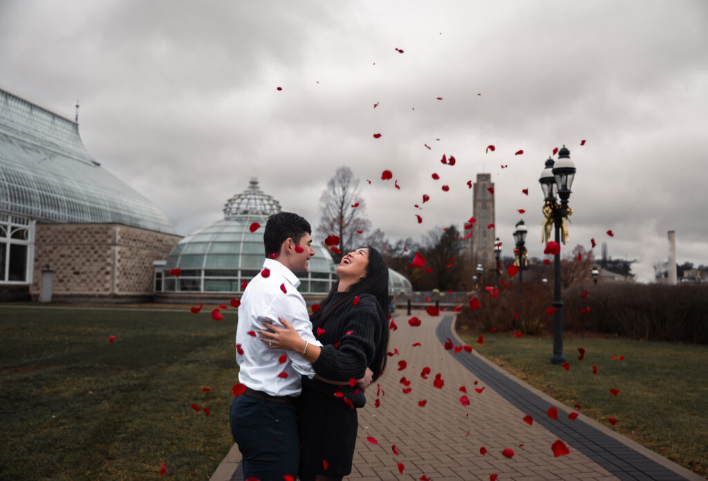 Couple celebrate their Proposal in front of Phipps botanical garden with roses in the air