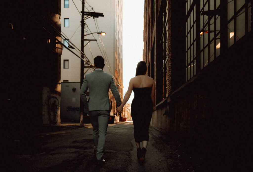 Couple holding hands walk down an alley in Pittsburgh strip district