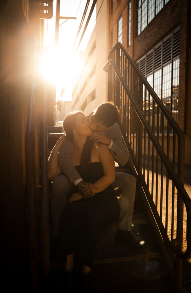 Couple embracing each other sitting at a staircase in Pittsburgh Strip District during golden hour