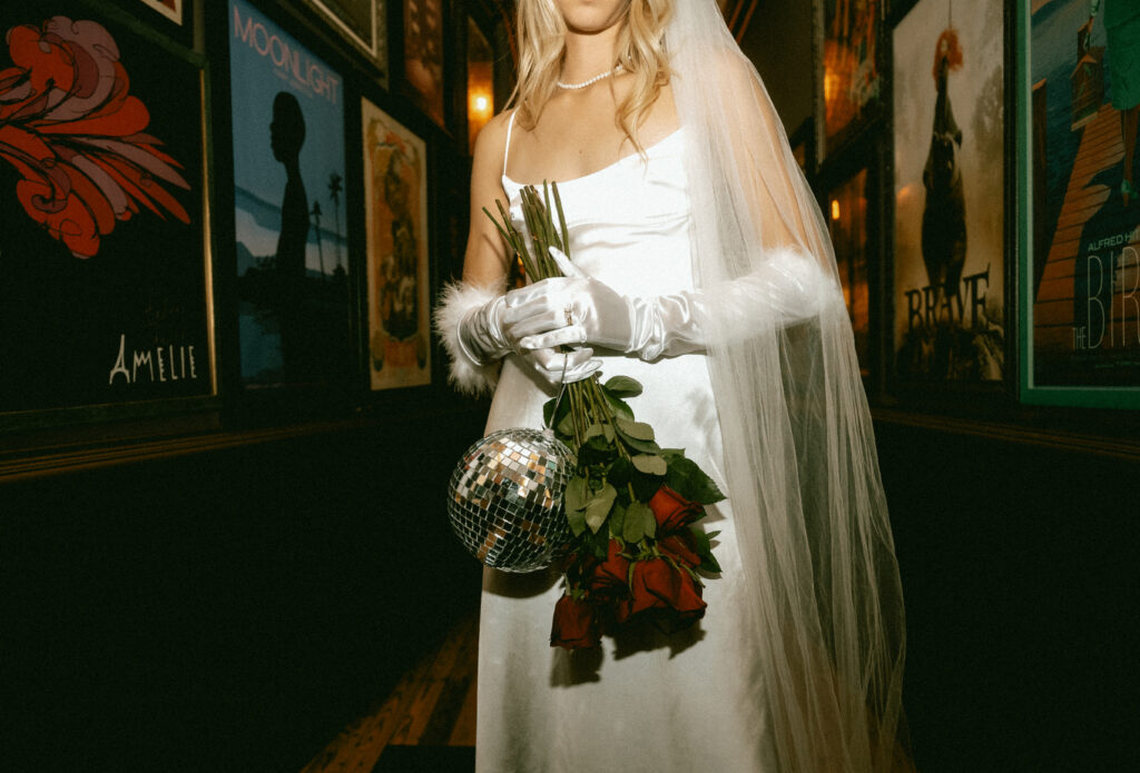 Bride holding disco ball and red roses at Row House Cinema in Lawrenceville
