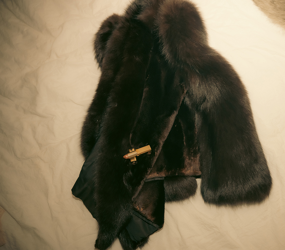 Vintage Winter Coat in a bed with lipstick on top
