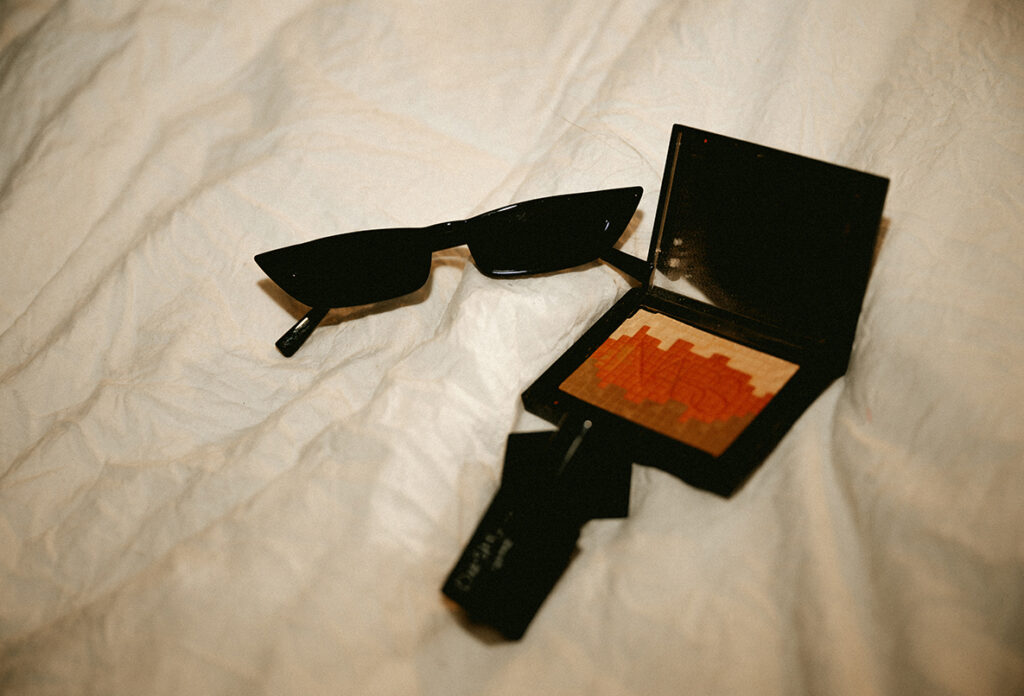Vintage sunglasses and blush on top of bed