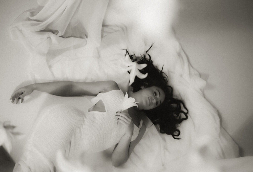 BW Bride laying down with flowers hanging from ceiling