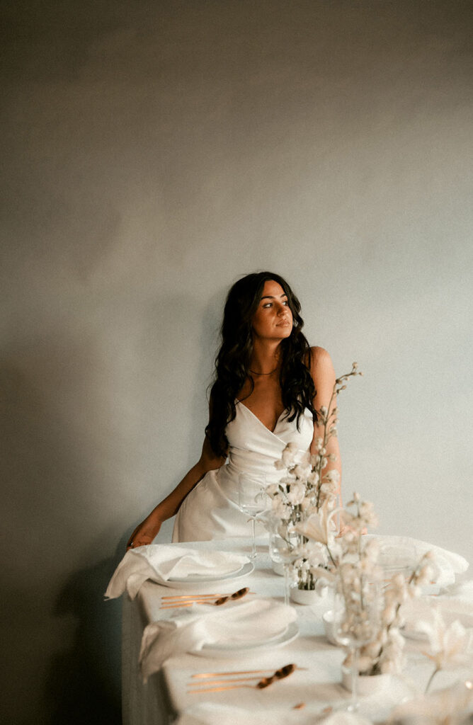 Bride Stands in front of Wedding Table Decor with flowers