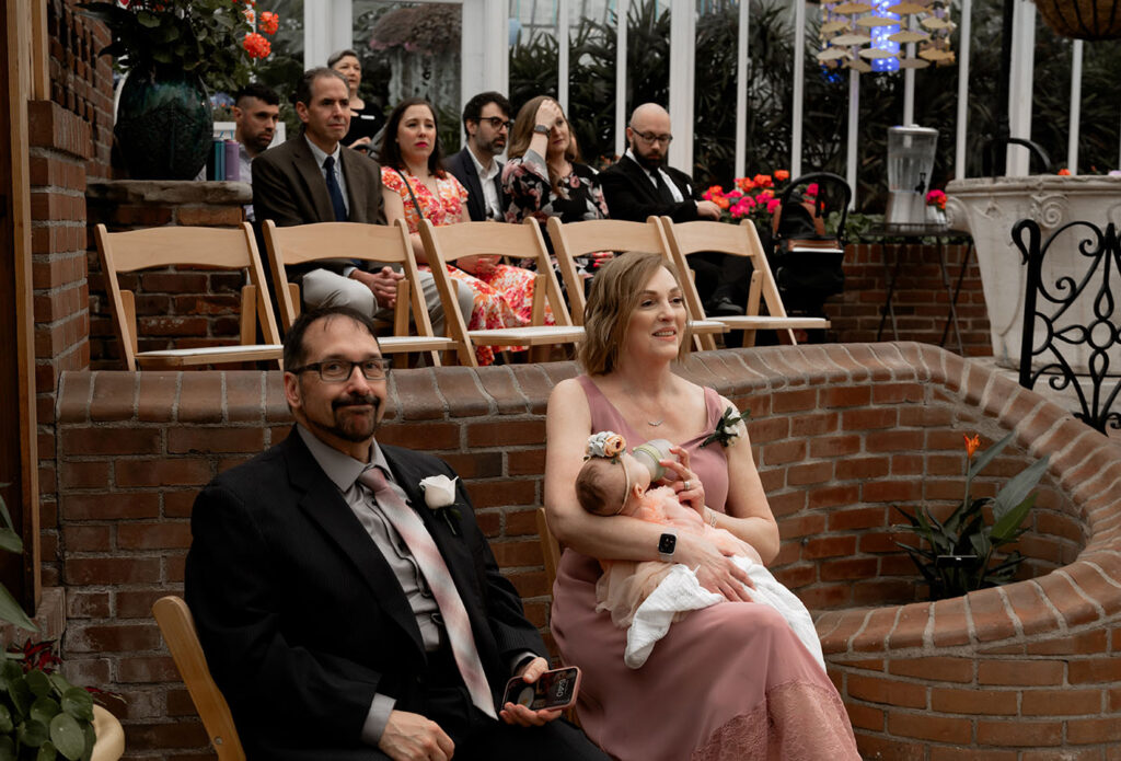 Mother of the bride looks at bride and groom getting married at Phipps Conservatory 