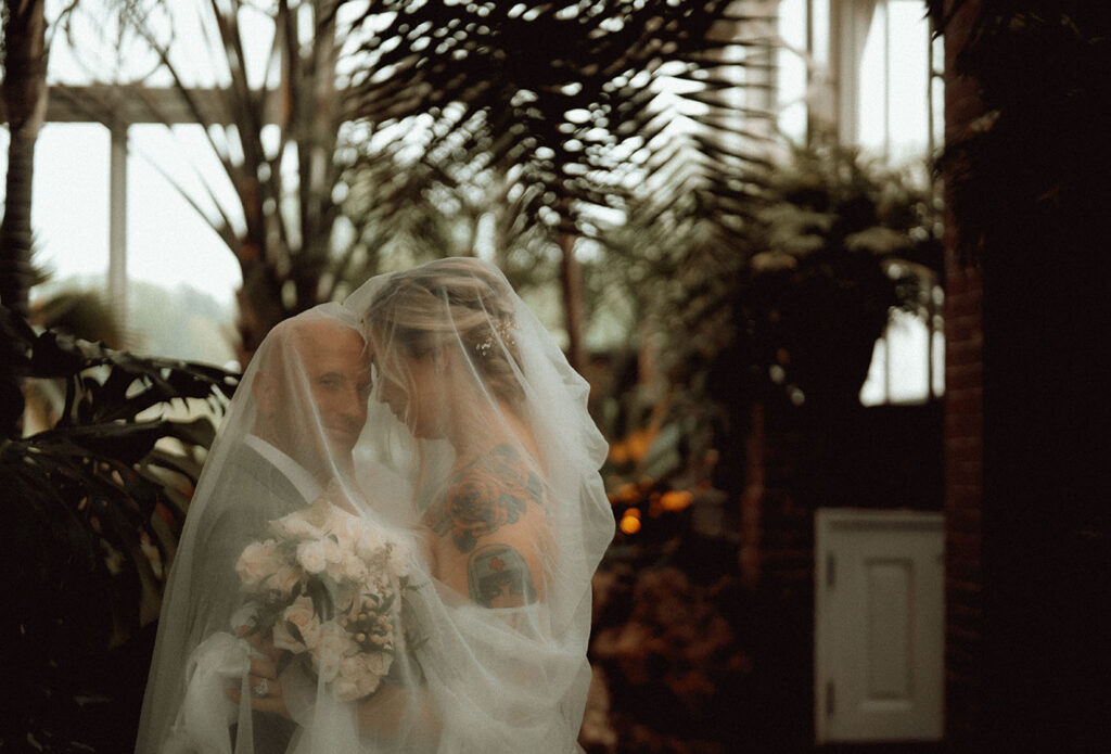 Bride and Groom under bride's veil at Phipps Conservatory