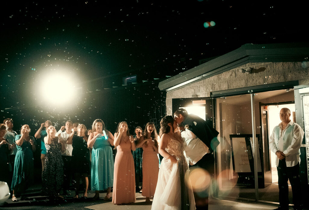 Bride and Groom kiss as they have a bubble exist with all their guests