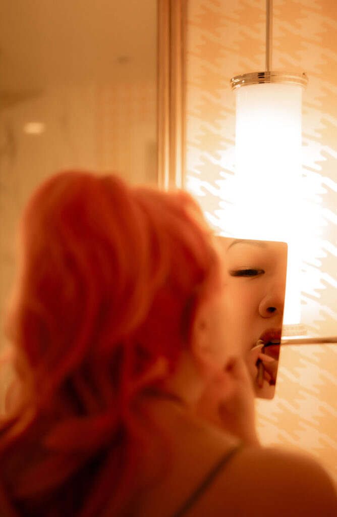 Bride lining her lips while looking at herself in mirror