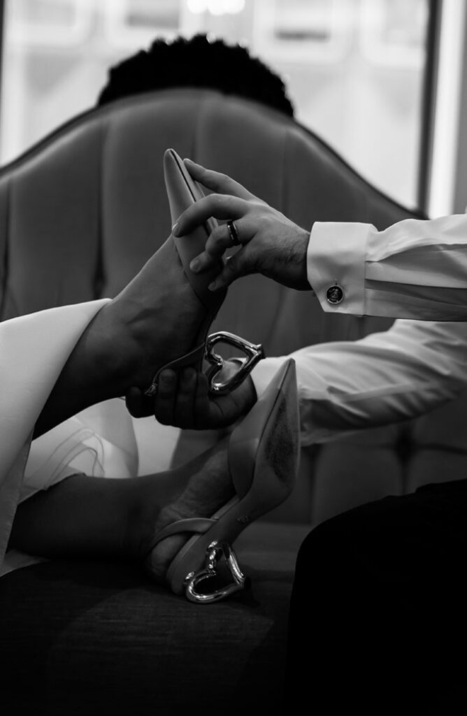 Groom puts shoes on for bride while sitting in Kimpton Monaco Hotel in Pittsburgh