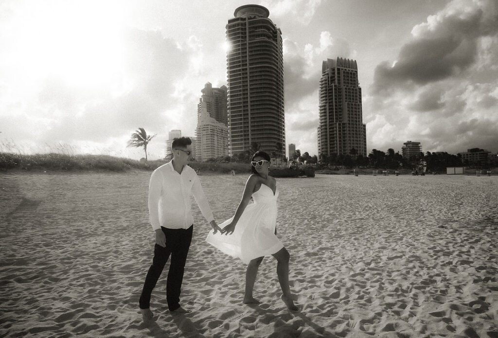 Couple walk towards the ocean with golden light behind