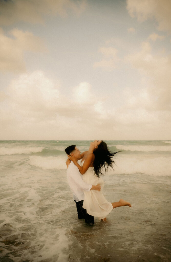 Couple laugh while holding each other in the ocean