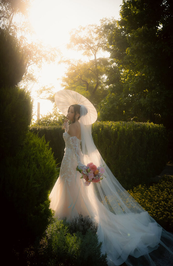 Bride walking holding umbrella against the sunset