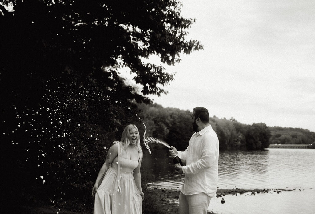 BW Couple pop Champagne bottle celebrating their engagement in Moraine State Park