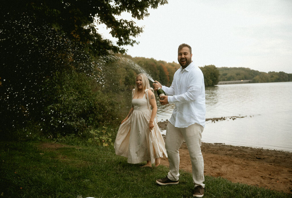 BW Couple pop Champagne bottle celebrating their engagement in Moraine State Park