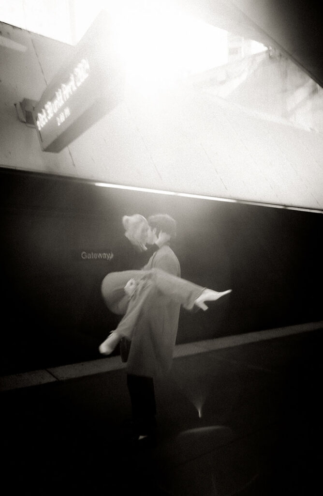 BW Man carrying girlfriend as they wait for their train.