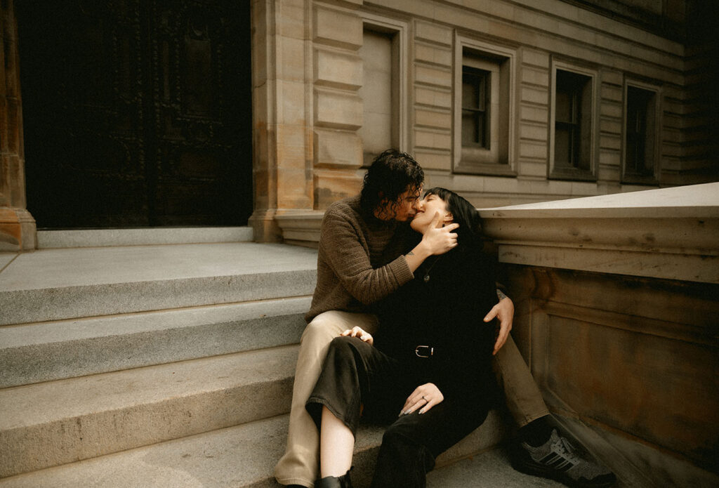 Couple sitting at Carnegie LIbrary Outside steps about to kiss