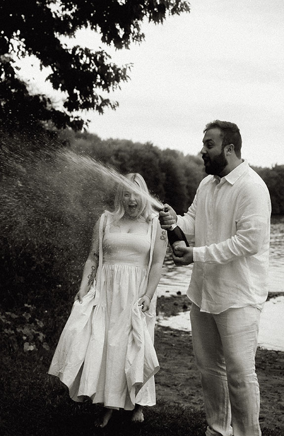 Couple popping a champagne bottle during Engagement at Moraine Park