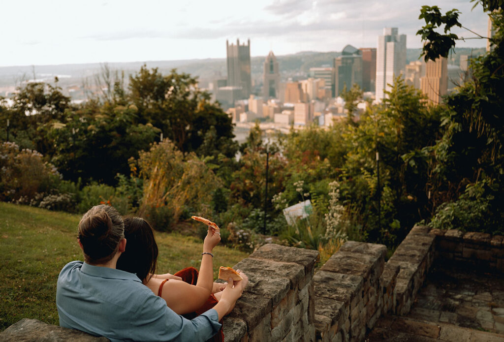 Couple Eating pizza as they watch the sunset in the Pittsburgh Skyline