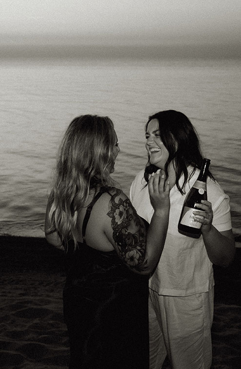 Couple popping champagne at Beach Engagement