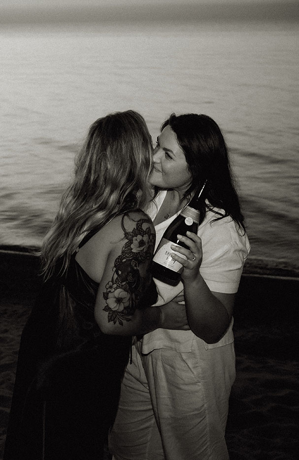 Couple popping champagne at Beach Engagement