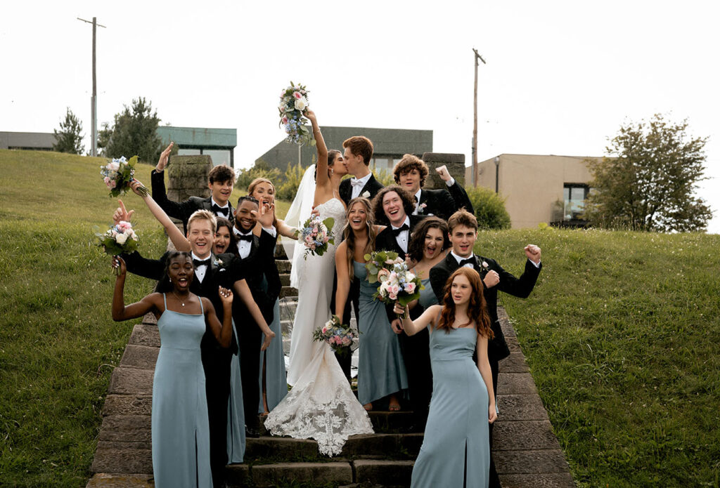 Bride and Groom Kiss While their Bridal Party Cheer at Emerald Park