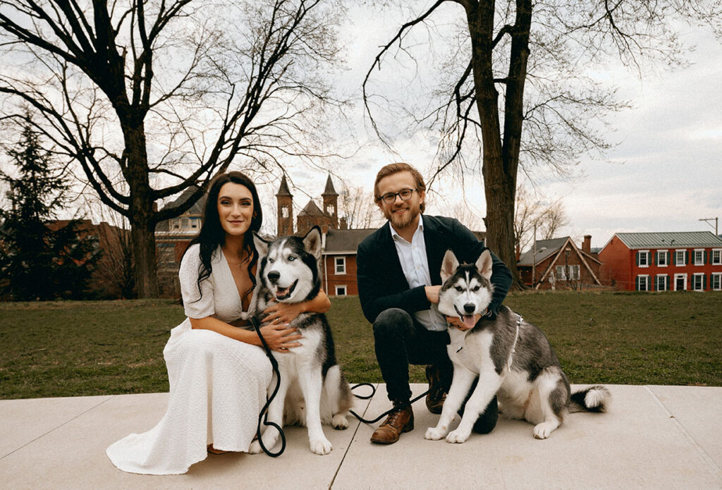 Couple kneeling beside their huskys for a sweet cuddle in a quiet side street in Lawrenceville.