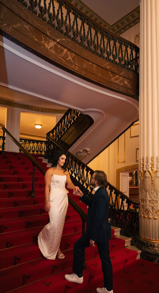 Couple looking at each other in the grand staircase at Heinz Hall.
