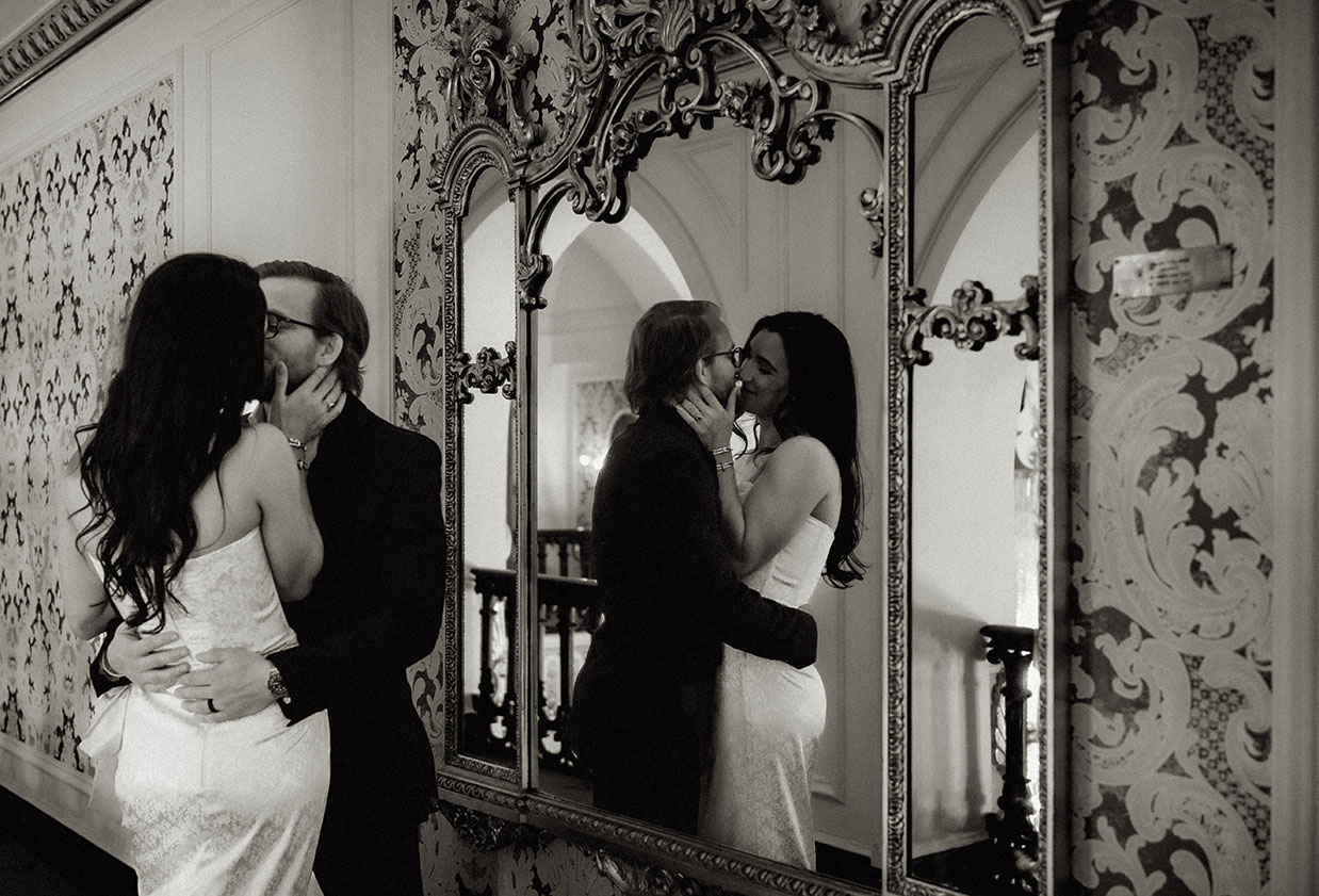 Editorial-style photo of groom-to-be adjusting his suit jacket in the mirror-lined hallway of Heinz Hall.