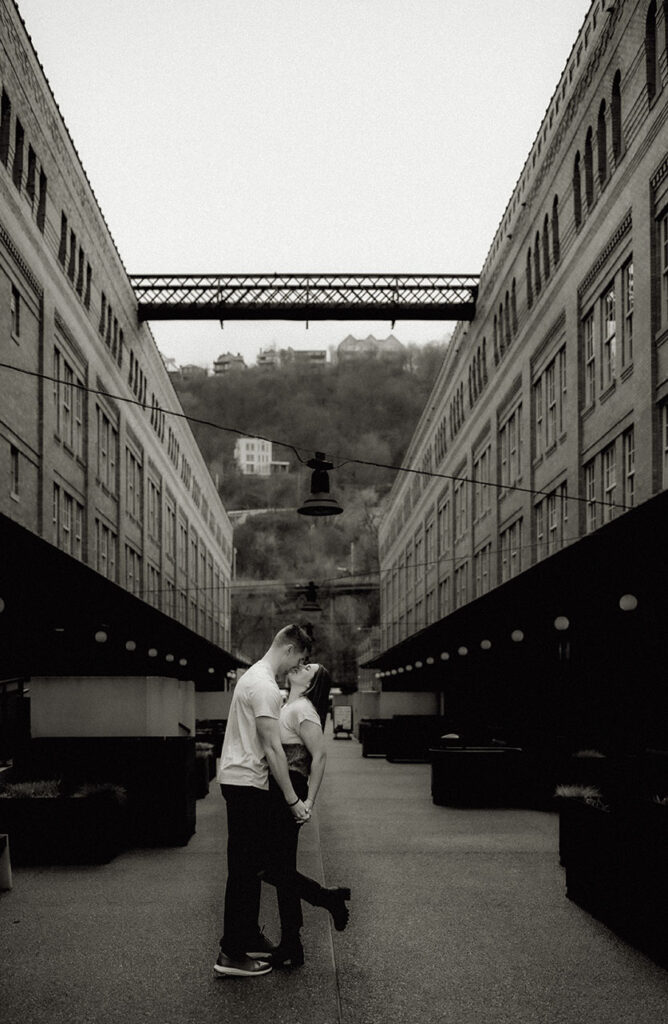 BW Artistic engagement photo of a couple in front of Pittsburgh’s downtown skyline from The Highline bridge platform.