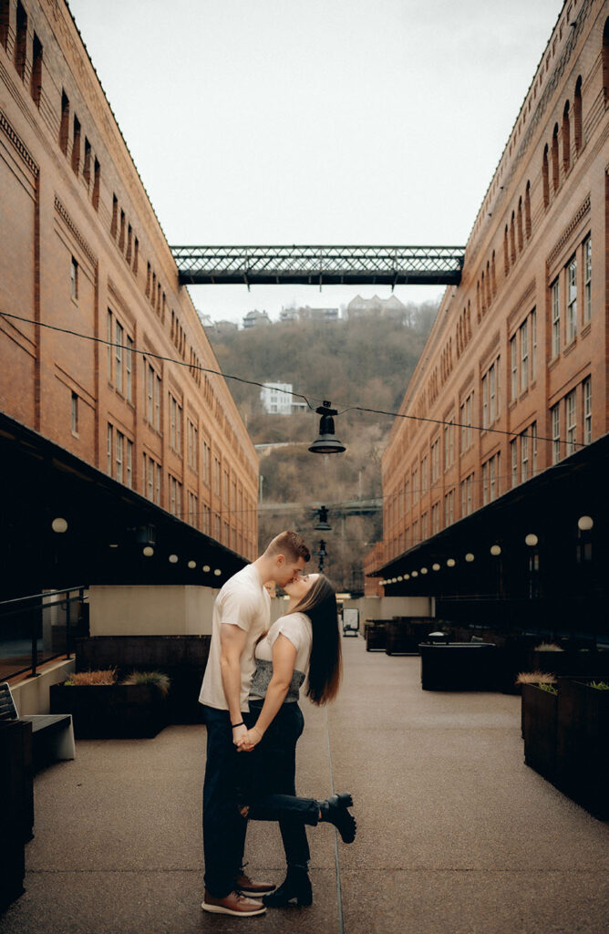 Artistic engagement photo of a couple in front of Pittsburgh’s downtown skyline from The Highline bridge platform.