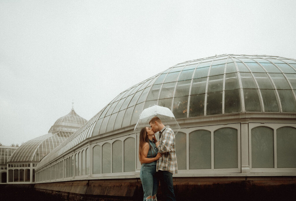 Intimate moment between couple during their rainy engagement session in Pittsburgh’s Schenley Park.
