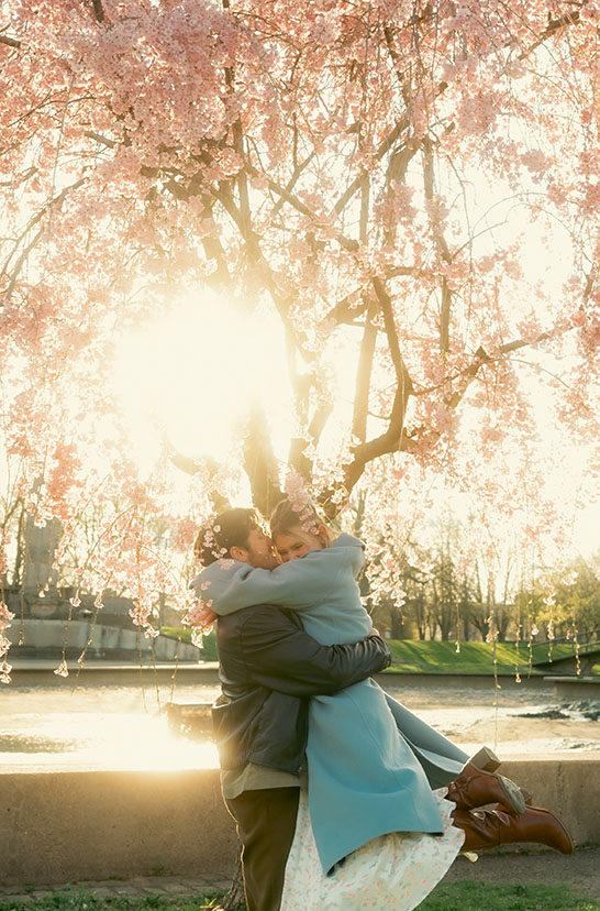 Romantic engagement photos with couple embracing under flowering trees in Allegheny Commons Park