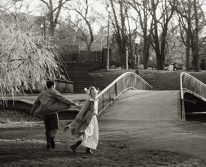 Romantic engagement photo in Allegheny Commons Park with couple embracing under lush tree canopy in Pittsburgh’s North Side.