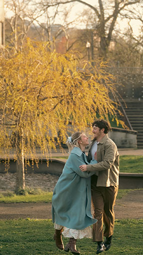 Wide shot of couple walking along the tree-lined paths of Allegheny Commons Park during their romantic spring engagement session in Pittsburgh.