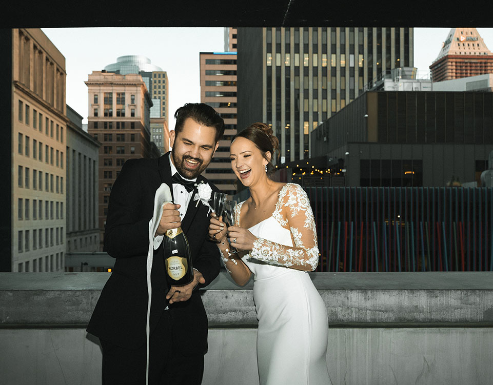Bride and Groom in their Wedding at the Contemporary Arts Center in Cincinnati popping a champagne bottle
